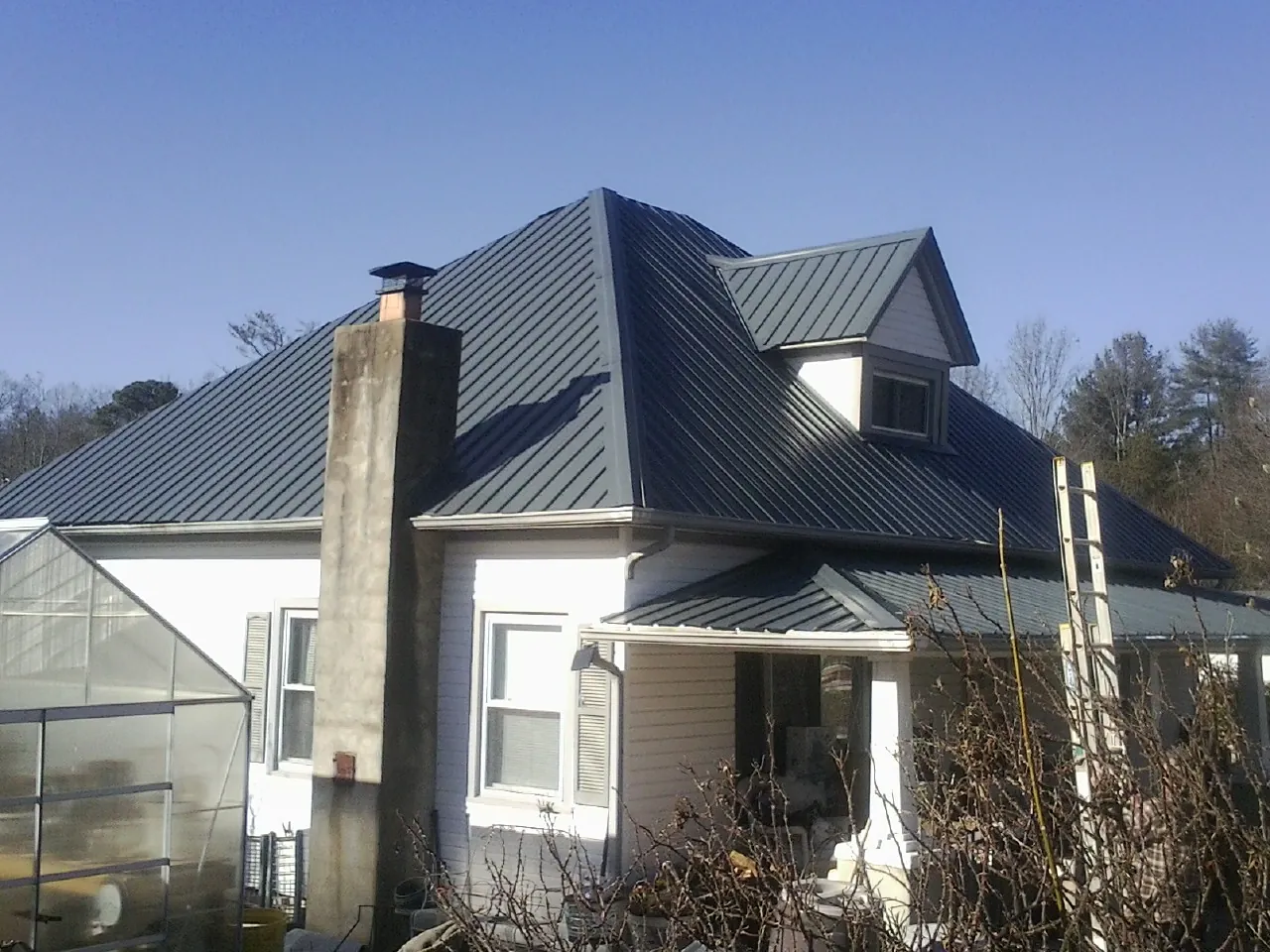 Dark blue standing seam metal roof on a white farmhouse with dormer — Slate & Tile Roof Repair by Roofing Brothers in Bush