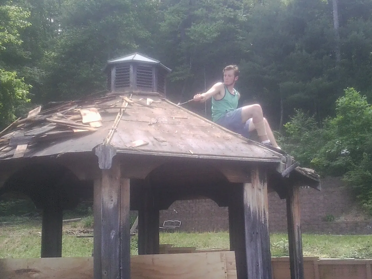 Tearing the old roof off a wooden gazebo before new shakes in Bush