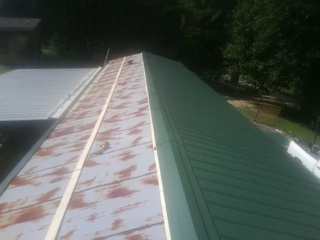 Old rusted panels beside newly installed green metal roofing — Wind Damage Roof Repair by Roofing Brothers in Bush