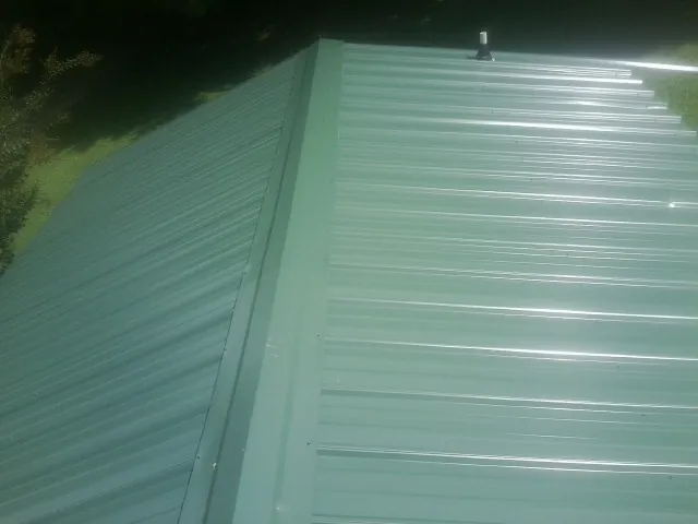 New green metal panels meeting at the ridge of a roof — Flat Roof Repair work by our crew in Bush