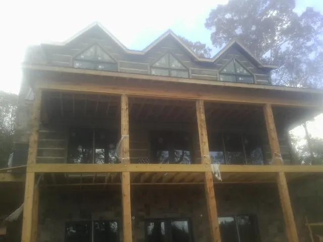 Dormers and porch framing on a large log home under construction — Roof Coating work by our crew in Bush