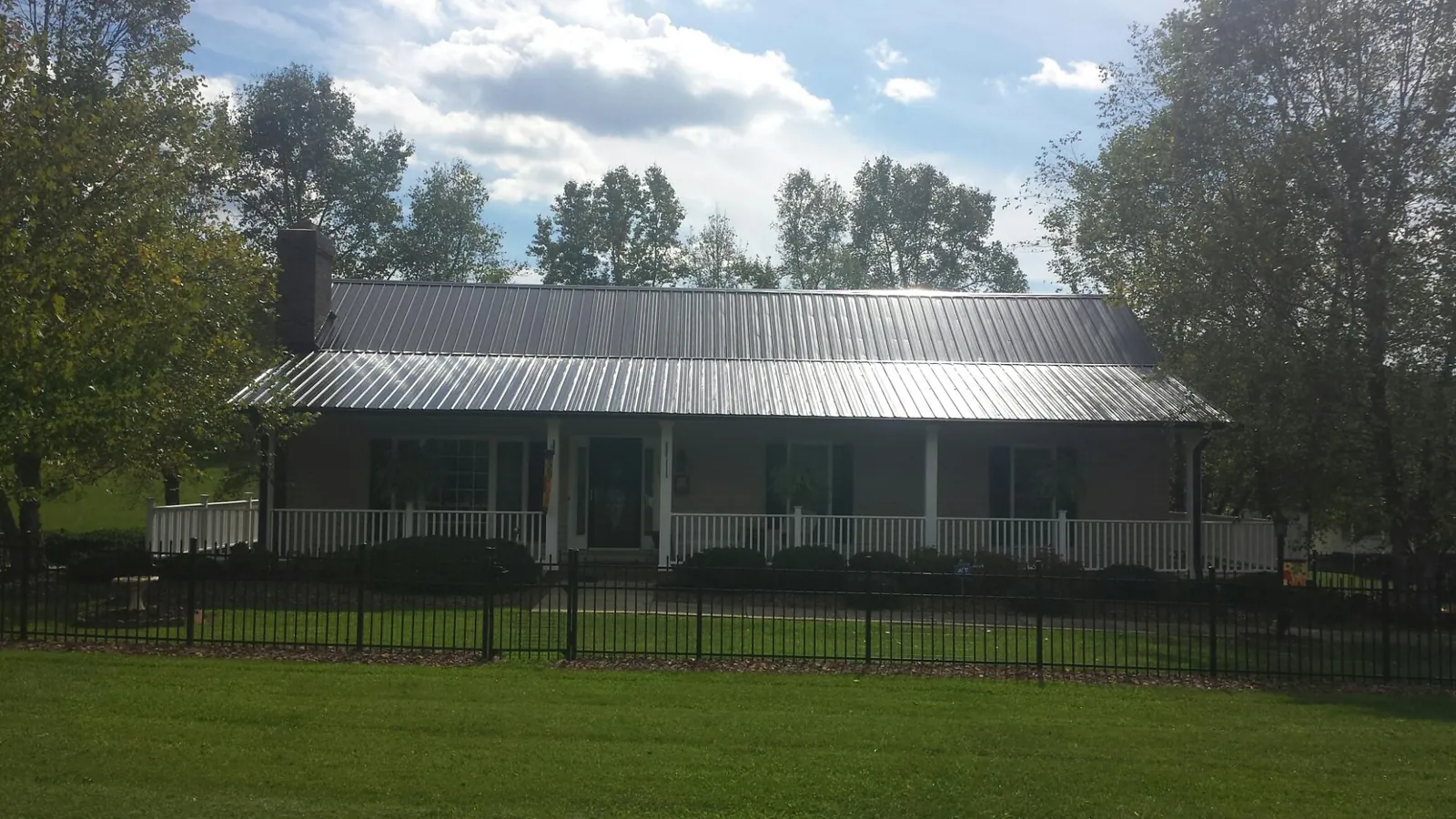 Gray metal roof on a brick ranch with a full width front porch — Gutter Guard Installation work by our crew in Bush