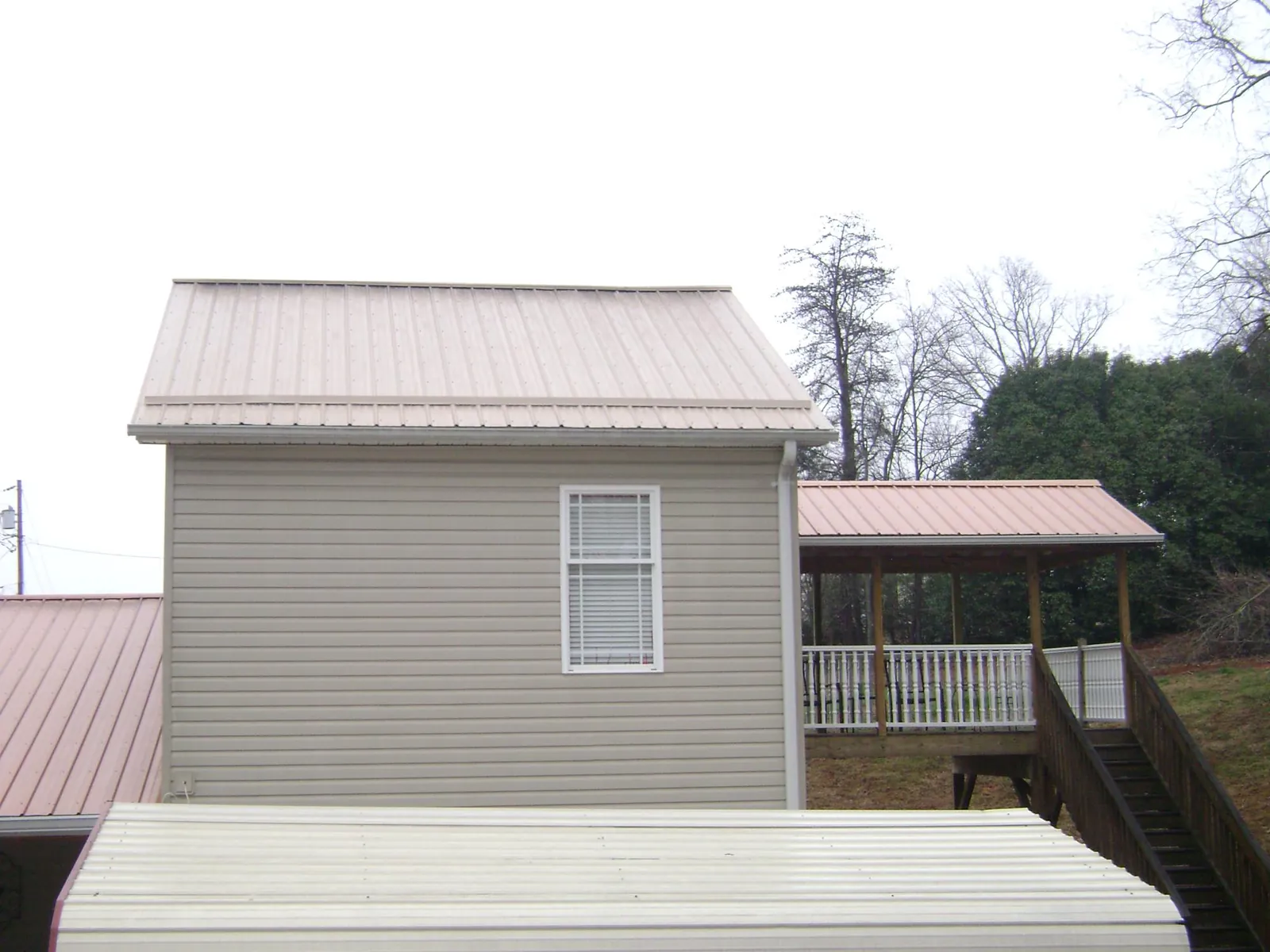 Tan metal roofs on a two story addition and attached porch, from a Roof Replacement job in Bush