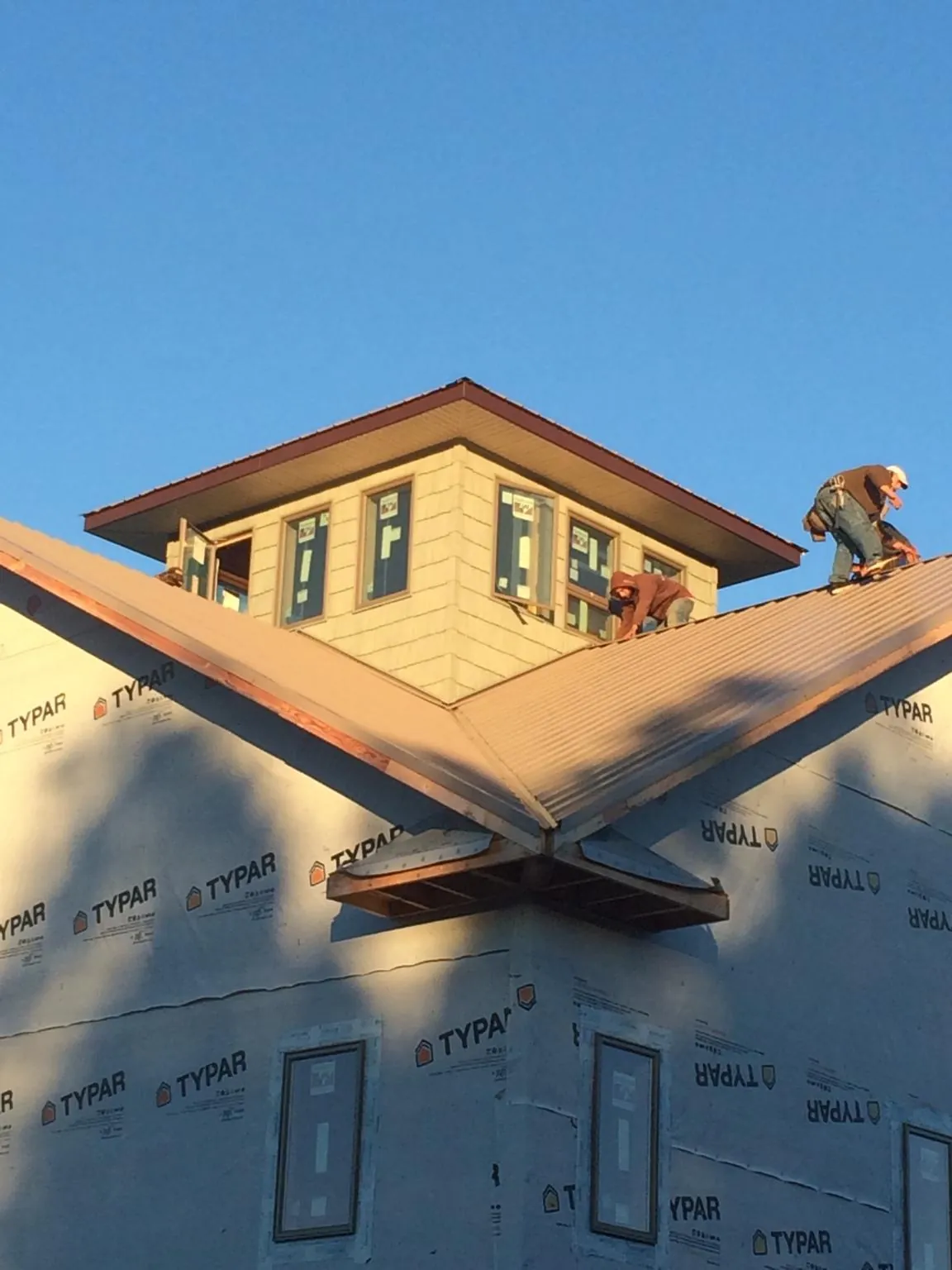 Roofers working around a rooftop cupola on a new metal roof at sunset — Roof Waterproofing in Bush by Roofing Brothers